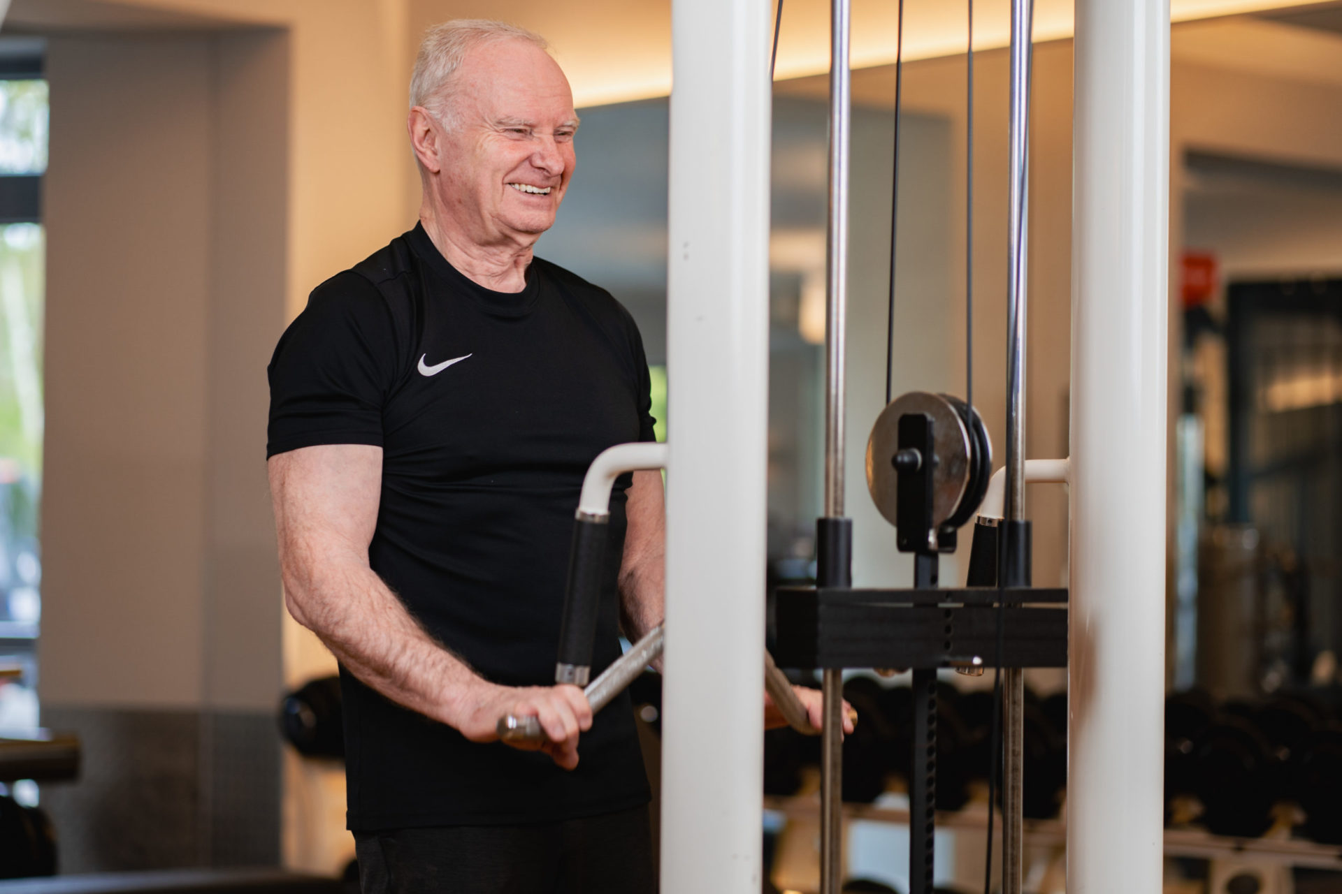 Ralf trainiert mit Freude seine Muskeln und stärkt seinen Körper, um im Alter aktiv und selbstbestimmt zu bleiben. Hier sieht man ihn am Kabelzug, wo Muskeltraining eine wichtige Rolle für seine Fitness spielt.