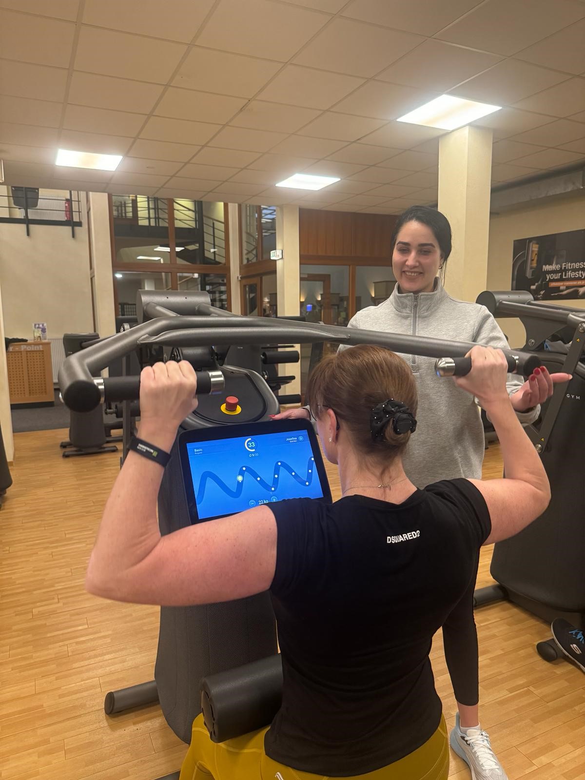 Persönliche Betreuung am EGYM-Gerät im Energeticum: Trainer und Mitglied arbeiten motiviert gemeinsam an individuellen Fitnesszielen.